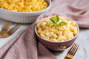 Mac and cheese with basil on top on a rustic wooden board
