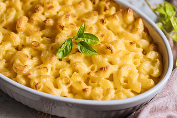 Mac and cheese with basil on top on a rustic wooden board