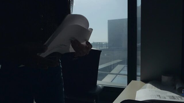 An undercover spy examines confidential documents. Female hands leafing through confidential documents and photographing them against the background of the window in the office