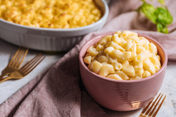 Mac and cheese with basil on top on a rustic wooden board
