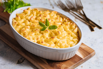 Mac and cheese with basil on top on a rustic wooden board