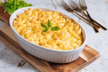 Mac and cheese with basil on top on a rustic wooden board