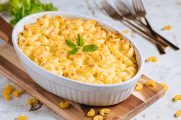 Mac and cheese with basil on top on a rustic wooden board