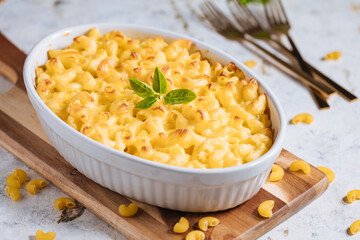 Mac and cheese with basil on top on a rustic wooden board