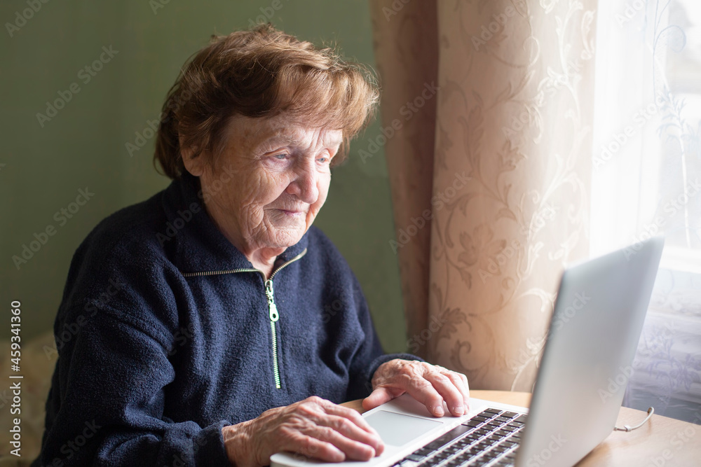 Wall mural Old retired woman studying working on the computer.