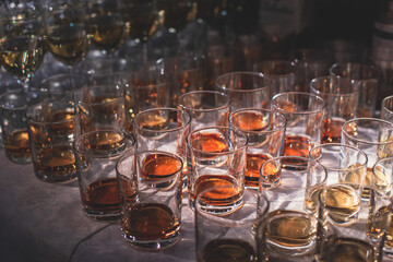 Beautiful row of different colored alcohol drinks on a party, whiskey, scotch whisky, bourbon, cognac, brandy and other cocktails, glasses on a bar counter table