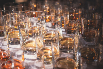 Beautiful row of different colored alcohol drinks on a party, whiskey, scotch whisky, bourbon, cognac, brandy and other cocktails, glasses on a bar counter table