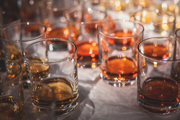 Beautiful row of different colored alcohol drinks on a party, whiskey, scotch whisky, bourbon, cognac, brandy and other cocktails, glasses on a bar counter table
