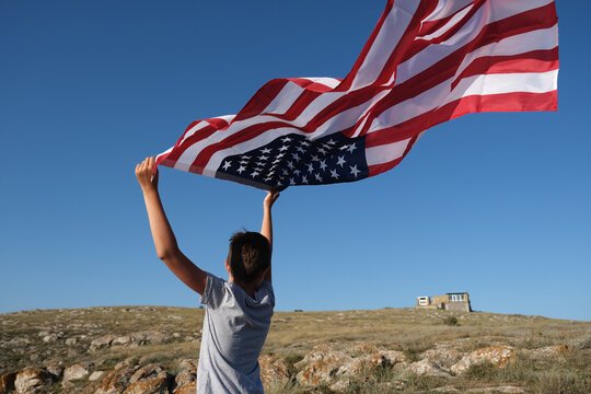 A boy holding waving US flag, beeng a patriot concept