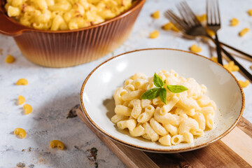 Mac and cheese with basil on top on a rustic wooden board