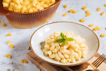 Mac and cheese with basil on top on a rustic wooden board