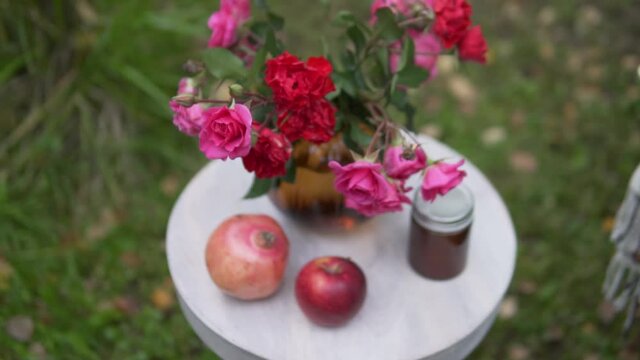 A beautifully decorated table outside in autumn, a vase of red roses and fruit on the table in a cafe in the autumn in the park.