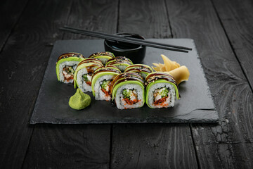 Japanese cuisine. Rolls on a square plate on a black table
