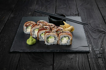 Japanese cuisine. Rolls on a square plate on a black table
