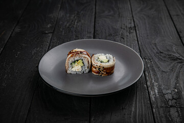 Japanese cuisine. Rolls on a round plate on a black table.
