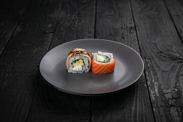 Japanese cuisine. Rolls on a round plate on a black table.
