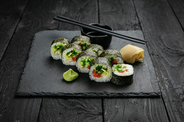 Japanese cuisine. Rolls on a square plate on a black table

