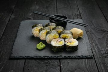 Japanese cuisine. Rolls on a square plate on a black table
