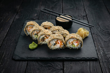 Japanese cuisine. Rolls on a square plate on a black table
