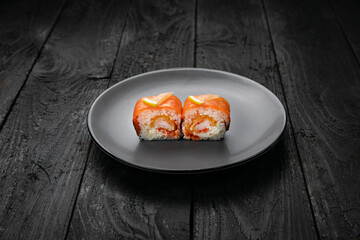 Japanese cuisine. Rolls on a round plate on a black table.
