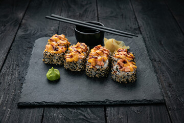 Japanese cuisine. Rolls on a square plate on a black table
