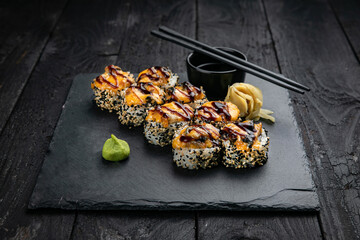 Japanese cuisine. Rolls on a square plate on a black table
