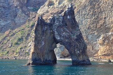 A rock in the form of a gate on the seashore. Golden Gate. Calm and clear weather. Suitable for backgrounds, photo wallpapers and landscape lovers.
