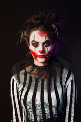 Woman with scary halloween makeup and red balloon striped blouse yellow big eyes hands with blood