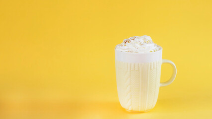 Pumpkin latte on yellow background in cozy mug. Image with copy space