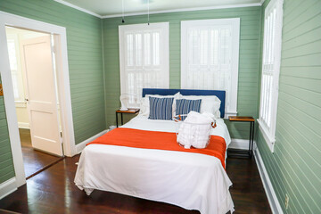 A master bedroom bedroom with a king sized bed and a fan at a short term rental small cottage style...