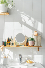 Shelf in white modern bathroom with zero waste cosmetic items and reusable bottles. Shadows on the wall. Wellness and sustainability concept