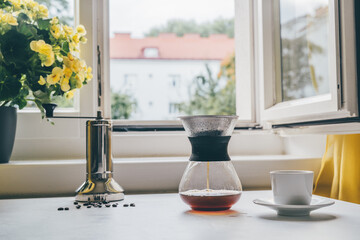 Close up of glass filter coffee maker at the kitchen in front of the open window. Making filtering espresso at home. Autumn concept