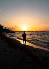 Hispanic man silhouette from the back looks at an incredible sunset on the coast of the Caribbean Sea