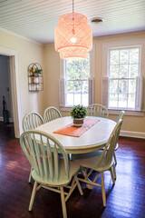 A small dining room with a statement rattan lighting ficture and a painted blue dining room table