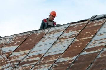 Repair of an old roof on the street. A view of an old tin roof made of rotten and rusty metal...