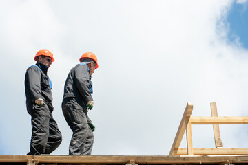 Repair of a wooden roof outdoors against a blue sky background. Two carpenters in special clothes...