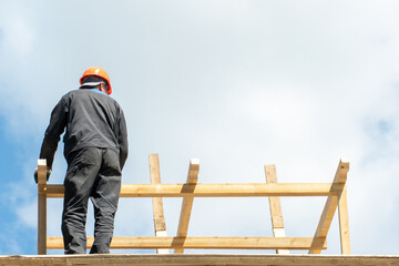 Repair of a wooden roof outdoors on a summer day against the background of blue sky and clouds. A...