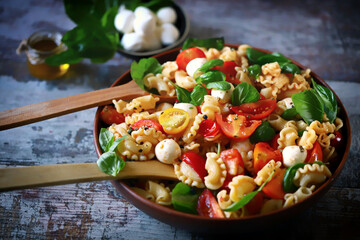 Selective focus. Pasta with tomatoes, basil and mozzarella balls. Italian food.
