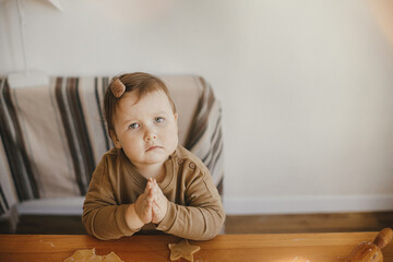 Fototapeta premium Cute funny little girl helps making christmas cookies on table. Adorable toddler daughter helping mother and cutting dough for gingerbread cookies. Lovely moments, holiday preparations