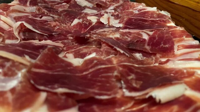 Close up of slices spanish dried pork also known as Jamon Serrano. Typical plate of tasty tapa of Iberian cured ham dish on the table, traditional food of Spain-Dan