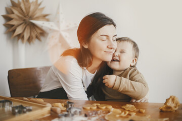 Cute little girl and mother making together christmas gingerbread cookies. Happy mom hugging adorable toddler daughter. Lovely Mommy daughter moments, happy family. Holiday preparation