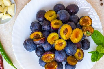 Cooking spicy plum sauce. Ingredients for tkemali on the table plate with plums, seasonings, close-up