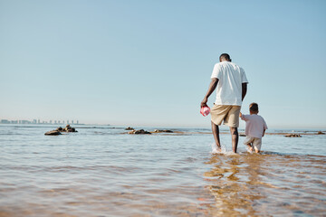 Minimal back view portrait of young father and son walking on water at beach, copy space