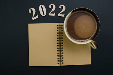 Close up of 2022 calendar and coffee mug on black background.new year 2022