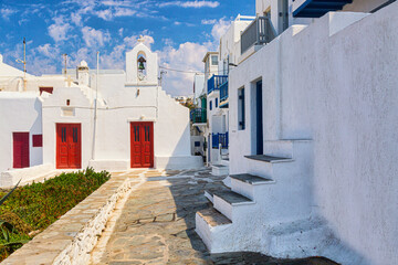 Famous old town narrow street with white houses and church. Mykonos island, Greece