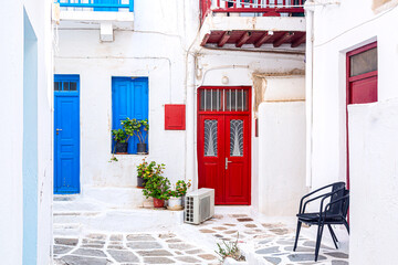 Famous old town narrow street with white houses and red door. Mykonos island, Greece - obrazy, fototapety, plakaty