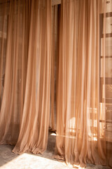 Airy peach tulle hangs as an interior decoration. Light fabrics are illuminated by the sun's rays
