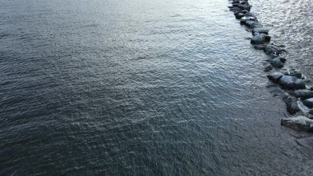A calming stock footage perspective of a body of water with a column of rocks that form the side of the shot as the view moves forward deeper into the mysterious unknown of the ocean