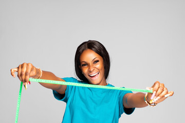 beautiful young black woman excitedly stretching a measuring tape in front of her from side to side