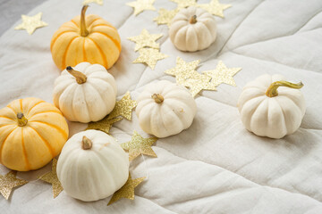 Sweet mini pumpkins and stars garland on a beige leaf blanket. Thanksgiving decoration.